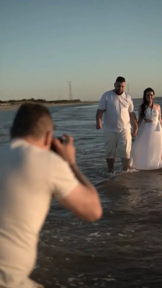 Marco fotografando casal na beira da praia